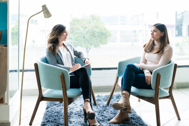 Young woman sharing her problems with female therapist during psychotherapy session in office