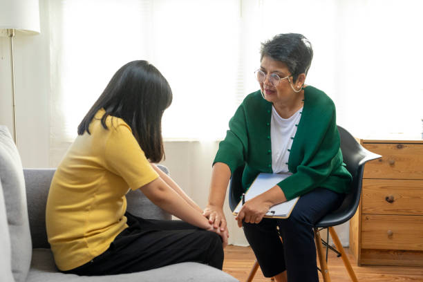 Depressed asian girl having consultation with psychologist doctor at clinic.